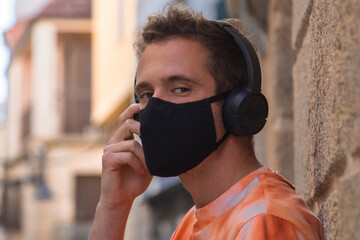 man through the monumental streets with medical mask and headphones in the new normal