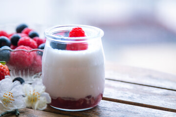 yoghurt with raspberries and blueberries on wooden background