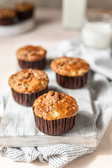 Tasty breakfast muffins with oat crumbs topping on white cutting board, light concrete background. 