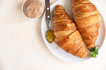 Croissants with jam and chocolate cream, light concrete background. Top view.