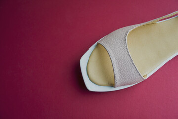 women's shoes of beige color on a red background. the shoes are removed from the top. shoes are angled to the horizon
