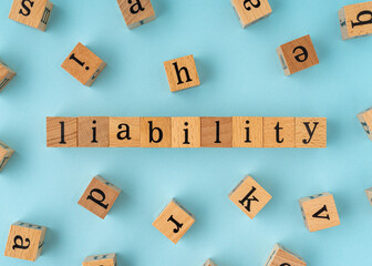 Liability word on wooden block. Flat lay view on blue background.