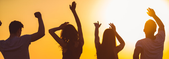 The four people dancing on the sunset background