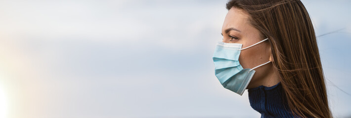 The attractive girl in medical mask standing outside