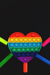 Top view of colorful anti stress sensory toy pop it rainbow heart on black background close up. And...