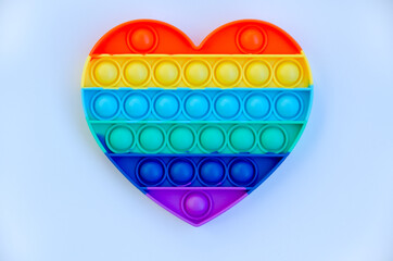 Top view of colorful markers and anti stress sensory toy pop it rainbow heart on yellow background close up. Creative and funny concepts of children toys. Popular toy. Trend toy 2021 year.