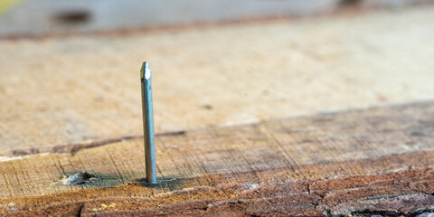 Ein senkrechtstehender Nagel auf einem alten Holzbrett
