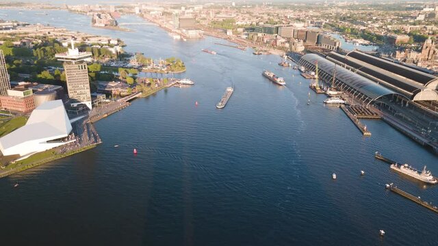 Aerial hyperlapse of Amsterdam central station and ferries crossing the river Ij at sunset. The Netherlands, europe.