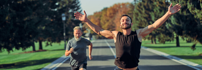 The young and old sportsmen running on the road