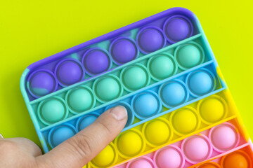 presses with a finger anti-stress toy pop it on the green background. Colorful poppit toy, bubble fidget, simple-dimple