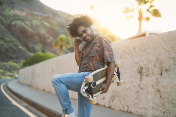 Tuinposter Happy Afro man having fun dancing and listening to music with wireless headphones during summer time - Youth people lifestyle concept © Alessandro Biascioli