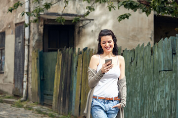 Young cute female using smartphone on the street.