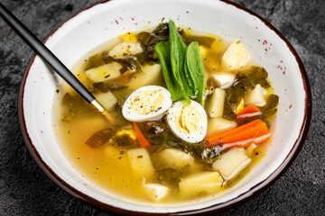 Diet sorrel soup with egg, in the bowl. Sorrel soup with egg, potatoes, carrots, parsley. Long banner format. top view