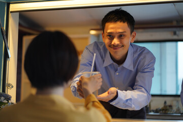 キッチンカーで飲み物を提供する男性