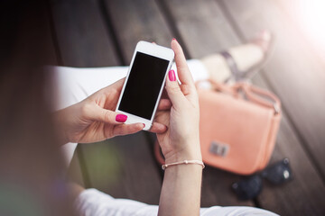 Girl using white mobile phone. Young girl sitting on wooden floor using her white mobile device. Vintage summer internet background. Summer vibes sunlight.