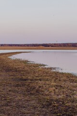 Spring flood on the river against the background of deciduous forest and sunset sky