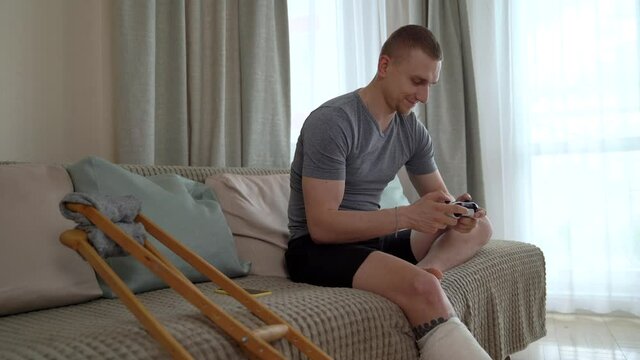A disabled man with a broken leg plays a console