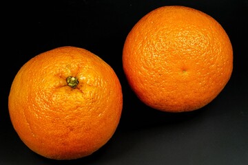 Two large ripe grapefruits on a black background