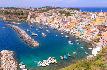 Panoramic view of beautiful of Procida, Italian Capital of Culture 2022: colorful houses, cafes and restaurants, fishing boats and yachts in Marina Corricella , in Gulf of Naples, Campania, Italy.