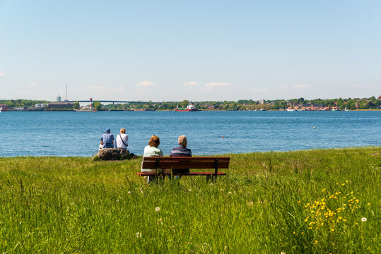 Am Strand von Kitzeberg zwei Sitzb&auml;nke mit &auml;lteren Personen und Blick &uuml;ber die Kieler F&ouml;rde auf die Einfahrt zum Kiel Canal