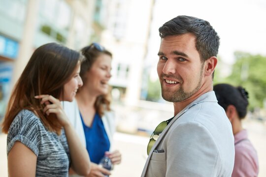 Outdoor portrait of happy young man meeting girls on the street.