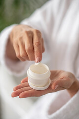 Close up picture of female's hand getting some cream from the jar