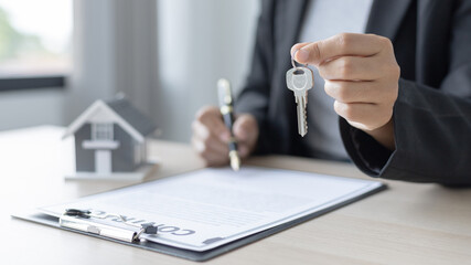 Sales manager or salesperson holds a demo house and has a home purchase contract with keys to...