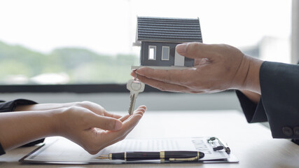 Sales manager or salesperson holds a demo house and has a home purchase contract with keys to...