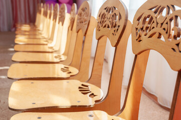 Fototapeta na wymiar Group of wooden chairs for preschoolers in kindergarten
