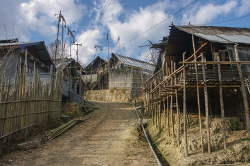 Fototapeta na wymiar View of a street with traditional houses in a typical hillside Apatani tribal village on the Ziro plateau, Arunachal Pradesh, India