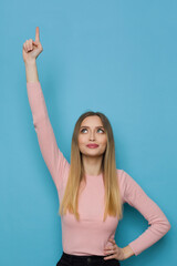 Cheerful Young Woman Is Pointing Up And Looking