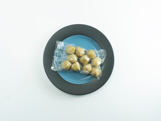 Indonesian meatballs or bakso or baso are wrapped in transparent plastic and placed on a ceramic plate