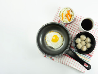 Indonesian Food | Omelet, pickled cucumber meatballs and meatball soup on a wooden cutting board on a white background