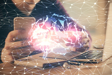 Double exposure of man's hand holding and using a digital device and brain hologram drawing. Data...