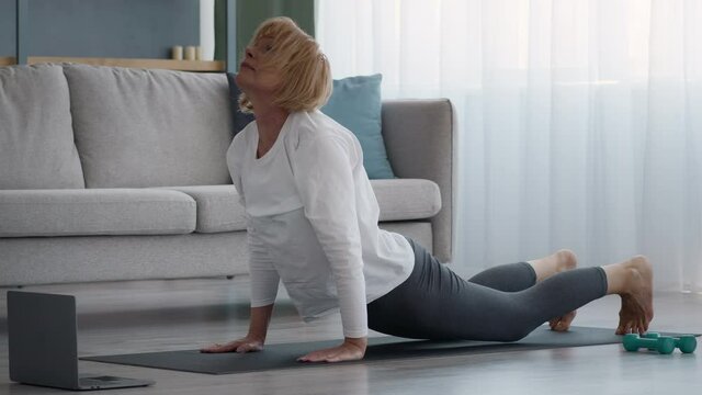 Senior Lady Doing Yoga Stretching Having Online Lesson At Home