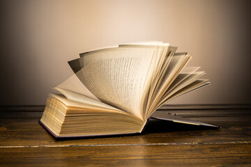 old book leafs through the pages on the table on a yellow background