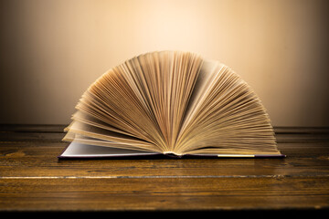 old book leafs through the pages on the table on a yellow background