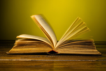 old book leafs through the pages on the table on a yellow background