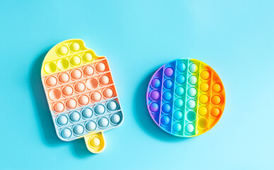 Fashionable touch bright toy antistress pop it blue background copy space. Silicone toy soft...