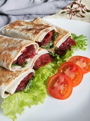Kebab on White Plate. A delicious Kebab wrap with spicy meat, lettuce, tomato, and sauce. Selective Focus