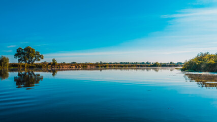 Aerial  view of a beautiful summer  landscape over river while dawn. Top view over river with a smooth water surface reflecting blue sky.