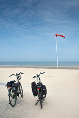 two bicycles on sandy beach and red  wind vane to forbid swimming in De Haan, Belgium