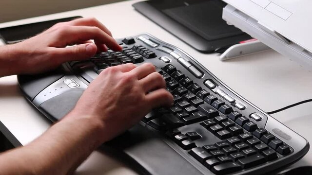 Business man typing on ergonomic keyboard and gaming with smartphone during home office at workplace with smartphone or modern computer equipment from home with European hands of a male person closeup