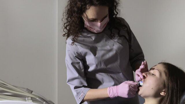 The orthodontist using dental impression tray on woman teeth. Dental spatula with print for dental implant.