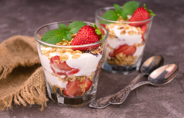 Healthy breakfast of strawberry granola and yogurt on a gray background.