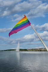Rainbow flag, a symbol for the LGBT community, waving in the wind with a cloudy background in the Geneva harbor, Switzerland