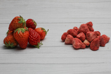Fresh and freeze dried strawberry on the light wooden background.