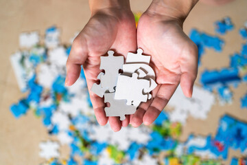 Woman hand holding jigsaw puzzle. Home puzzle game. Autism awareness. Mental health care concept with jigsaw pattern supported by family caregiver parent. Family and parent concept.