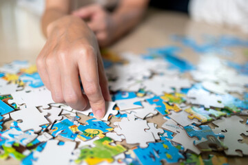 Mother and son lying on the floor doing jigsaw puzzles game. A boy finding a piece of puzzle and put it together. Kid category a part of puzzle by color. Learning and education concept..