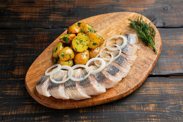 Salted herring with spice, herbs and onion on dark wooden background
